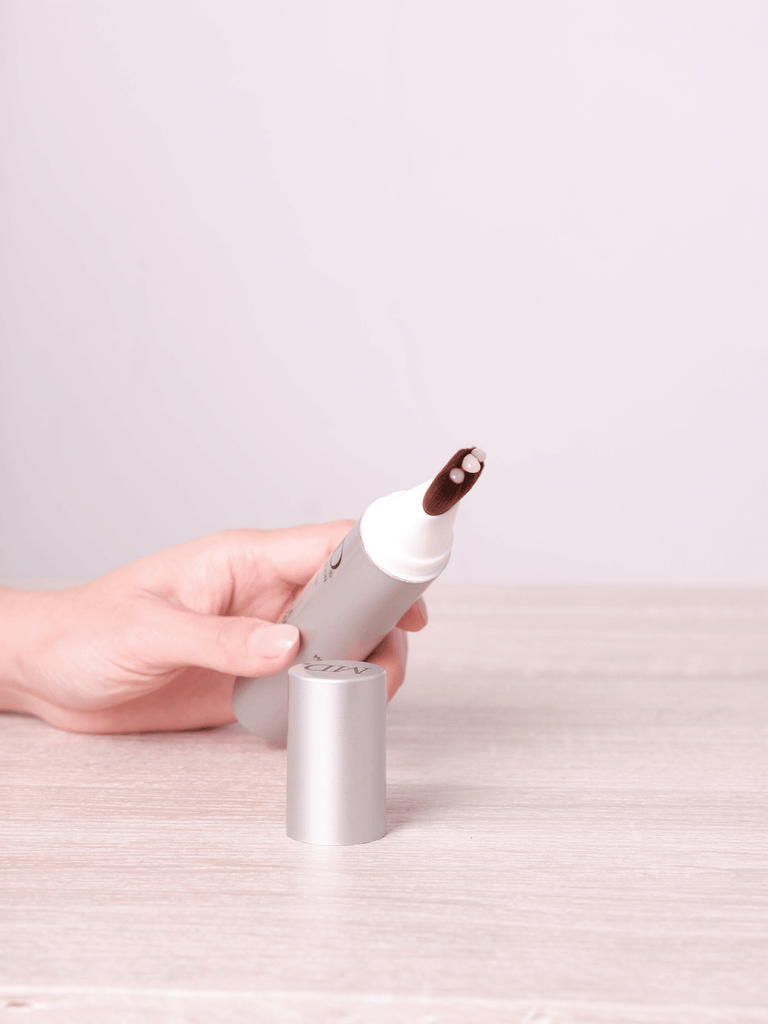 Hand holding MD® Follicle Energizer with visible serum on precision brush applicator – MD Hair targeted treatment