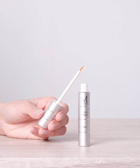 Hand holding MD Lash Factor precision tip applicator for 6-month lash growth serum